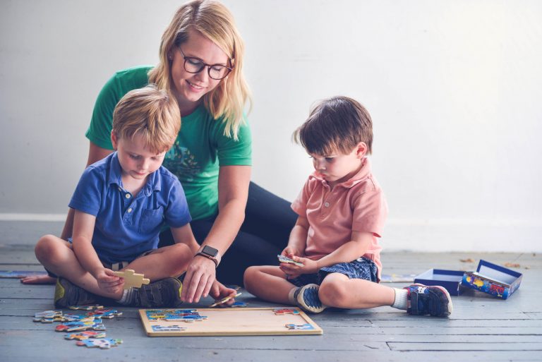 babysitter with two boys completing a puzzle