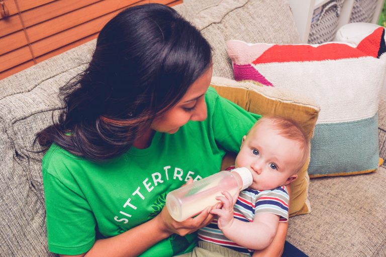 babysitter giving bottle to a baby