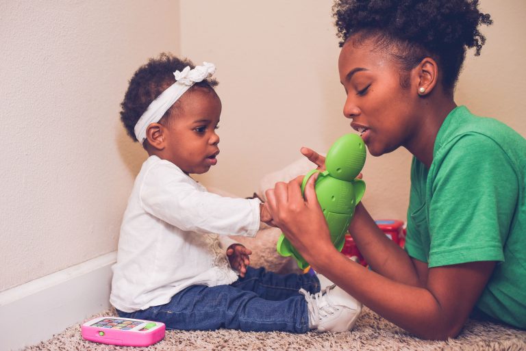 female babysitter and female toddler playing with toys