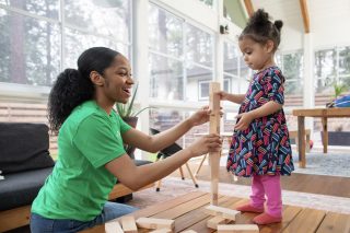 a preschool teacher builds with blocks with a child