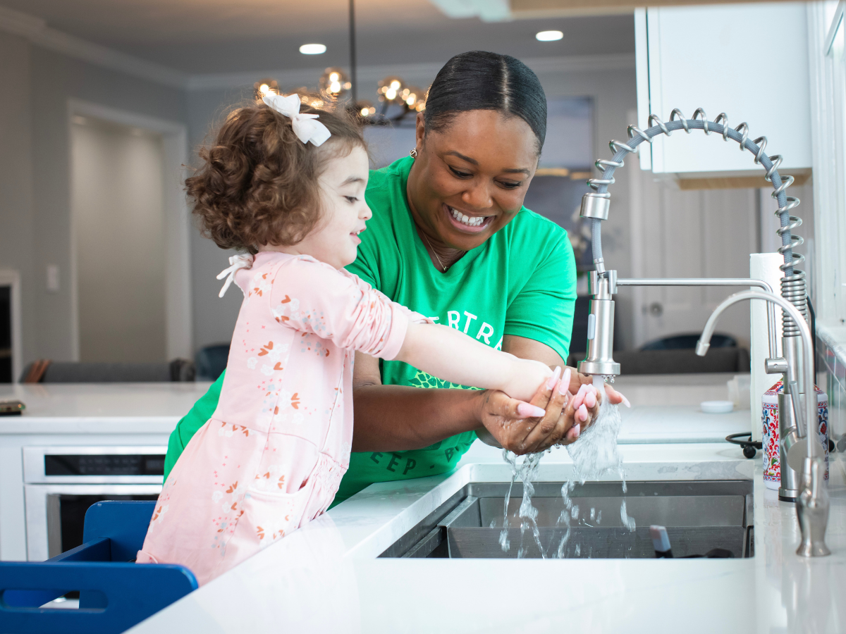 babysitter helping girl wash her hands