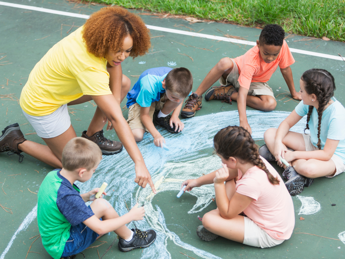 Camp counselor and kids drawing with chalk