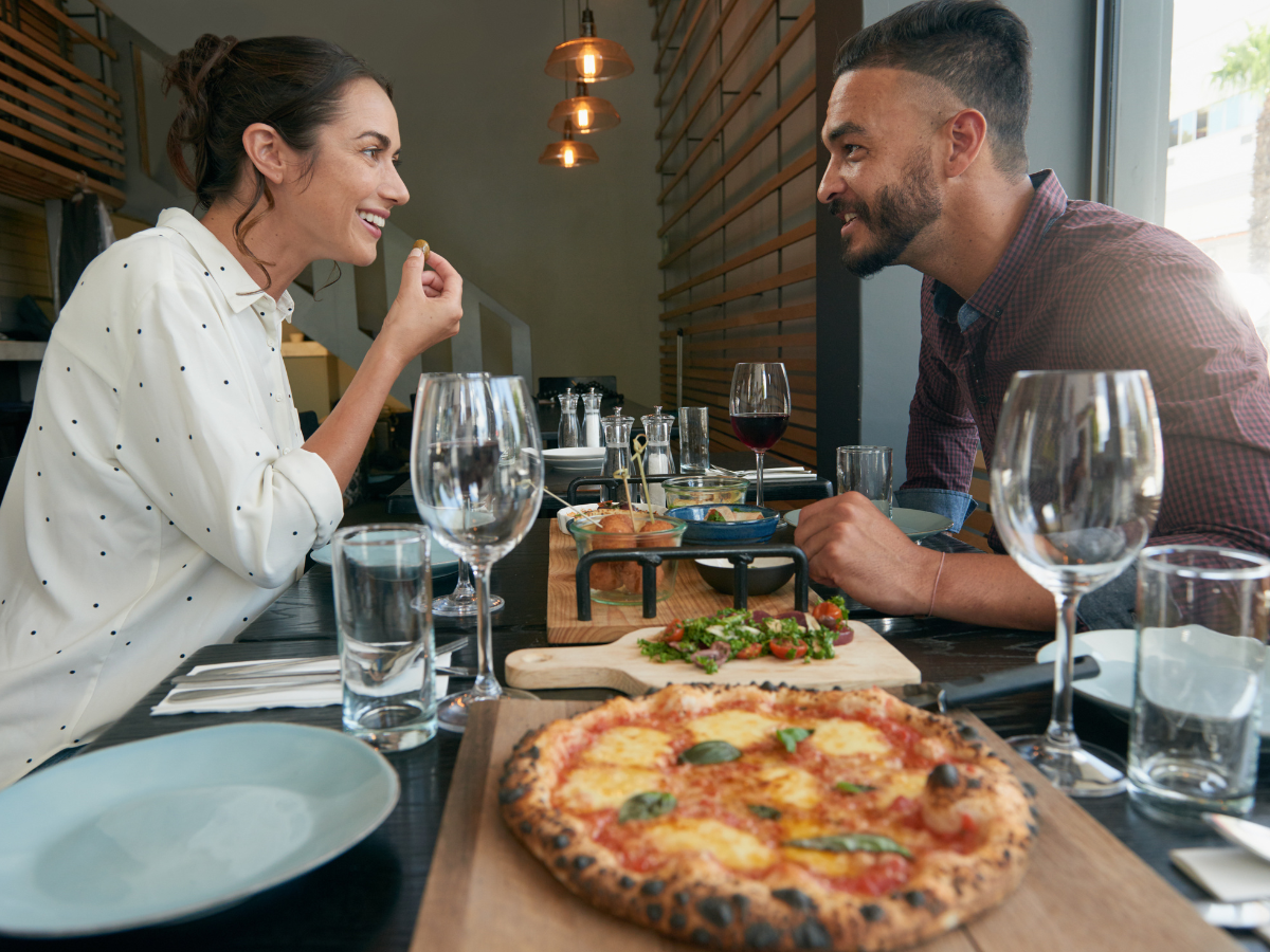 couple on a date night eating pizza and drinking wine