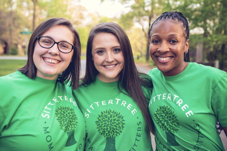 Three smiling women wearing green SitterTree T-shirts standing outdoors with trees and a blurred background: First-time babysitter tips