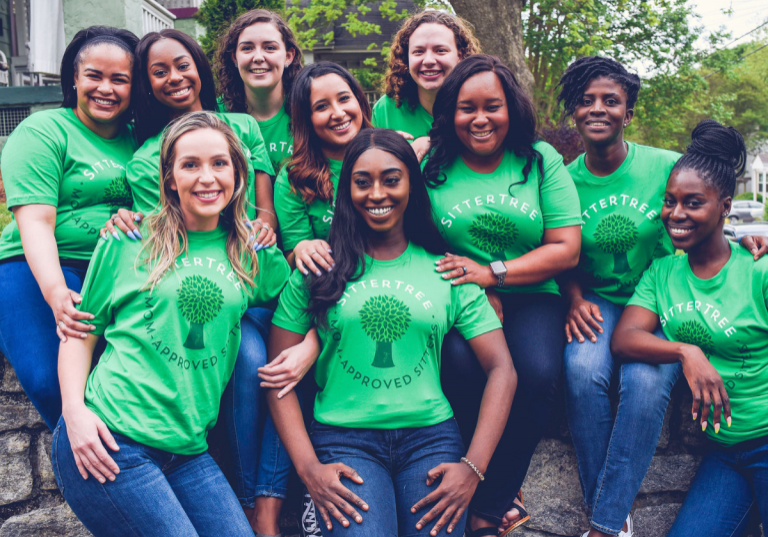 How to gain babysitting experience: A group of smiling SitterTree sitters wearing green 'Mom-Approved Sitter' T-shirts, sitting together outdoors, showcasing community and trust